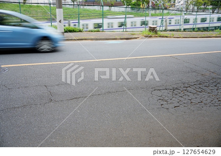 風を切って駆け抜ける車とひび割れたアスファルト 風を切って駆け抜ける車とひび割れたアスファルト 127654629