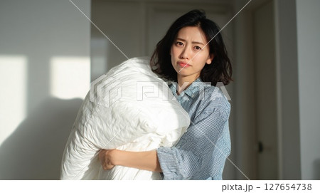 掛け布団の収納に困る女性 127654738