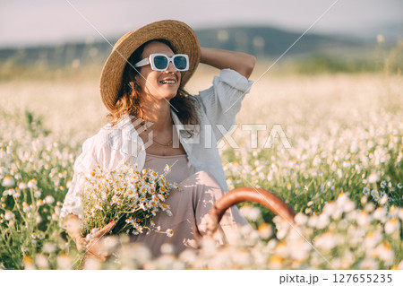 Daisy Woman Flowers: Smiling woman sits in daisy field during daytime holding bouquet. 127655235