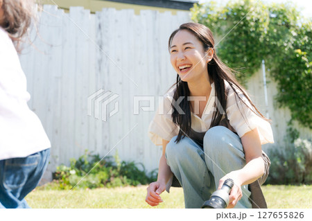 庭で遊ぶ子を見守るママ 127655826