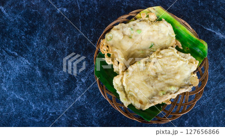 Traditional Indonesian snack tempe mendoan kebumen, fermented soybean cake deep fried in flour beter with green onions served on bamboo plate over dark background Traditional Indonesian snack tempe mendoan kebumen, fermented soybean cake deep fried in flour beter with green onions served on bamboo plate over dark background 127656866