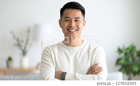 落ち着く空間で腕をくんで笑う男性 127658305