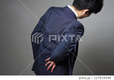 ビジネスマン　腰痛　後ろ姿　黒背景 127658496
