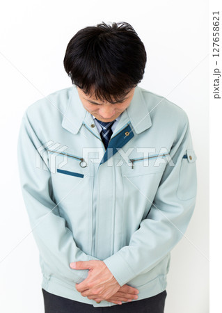 グリーンの作業服を着て謝罪をするミドル男性ビジネスマン 127658621