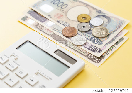 黄色背景に日本のお金と電卓 127659743