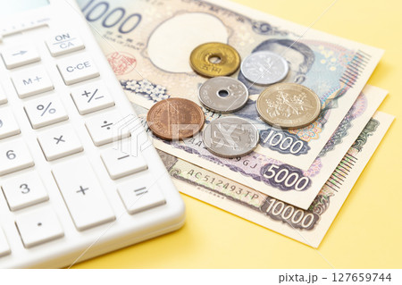 黄色背景に日本のお金と電卓 127659744