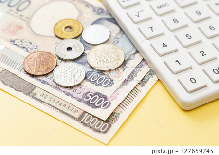 黄色背景に日本のお金と電卓 127659745