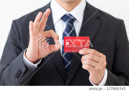 クレジットカードを持って丸サインをするスーツ姿のビジネスマン男性 127660141