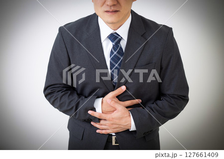 腹痛に苦しむスーツ姿のミドル男性ビジネスマン 腹痛に苦しむスーツ姿のミドル男性ビジネスマン 127661409