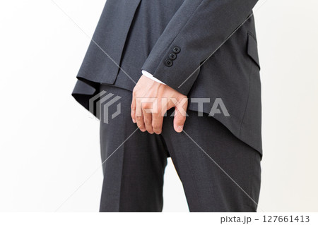お尻を押さえて苦しむスーツ姿のミドル男性ビジネスマン 127661413