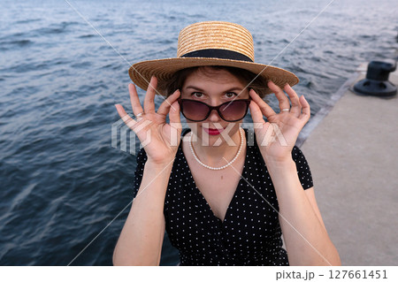 Portrait of woman adjusting sunglasses while facing the camera. Portrait of woman adjusting sunglasses while facing the camera. 127661451