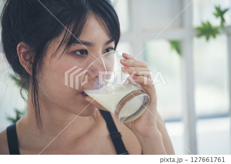 Women hands holding white glass of milk pouring from bottle. Asian women smile laugh look at camera health care home fitness lifestyle. Beautiful female drinking fresh milk low-fat dairy free lactose 127661761