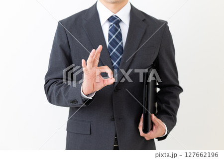 黒いファイルを持って丸サインをするスーツ姿のミドル男性ビジネスマン 黒いファイルを持って丸サインをするスーツ姿のミドル男性ビジネスマン 127662196
