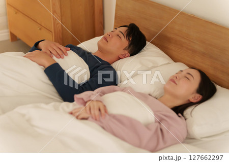 ダブルベッドで一緒に寝る夫婦 127662297