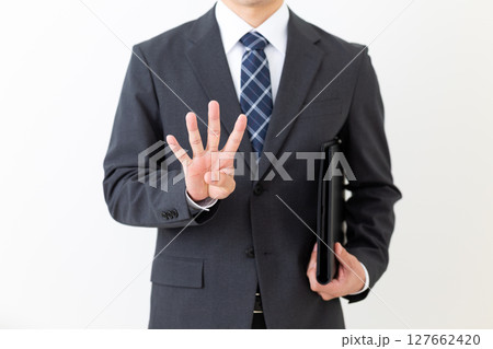 黒いファイルを持って4本指を立てるスーツ姿のミドル男性ビジネスマン 黒いファイルを持って4本指を立てるスーツ姿のミドル男性ビジネスマン 127662420