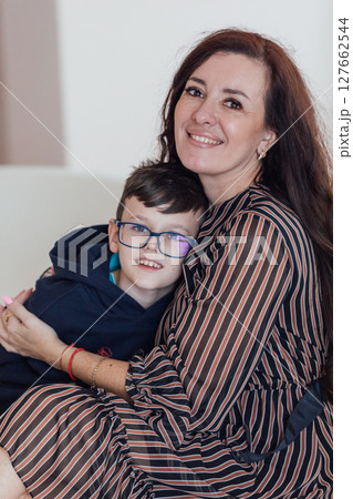 Brunette mom hugging her son with glasses and smiling Brunette mom hugging her son with glasses and smiling 127662544