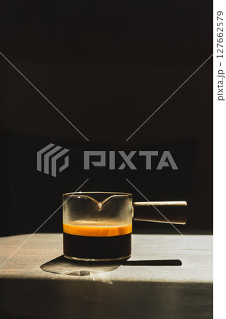 Espresso coffee in a glass cup on a dark background in vertical. Espresso coffee in a glass cup on a dark background in vertical. 127662579