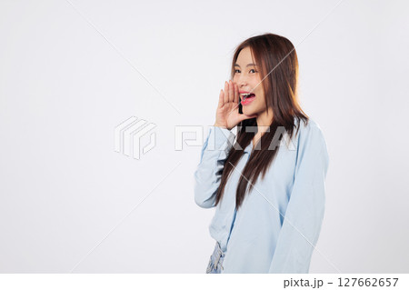 Excited woman shouting loudly with hands over mouth, second woman reacts to news with cheerful expression, both full of emotion on isolated white studio background. 127662657