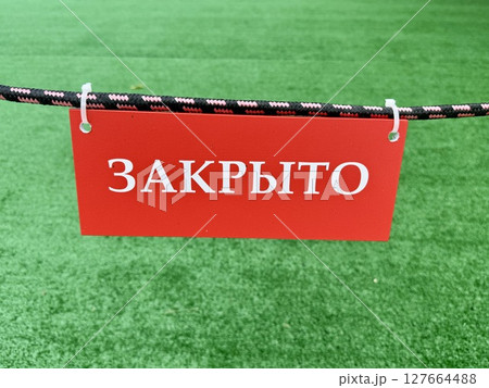 a sign with the inscription closed on the background of an artificial green lawn on a warm summer day. High quality photo 127664488