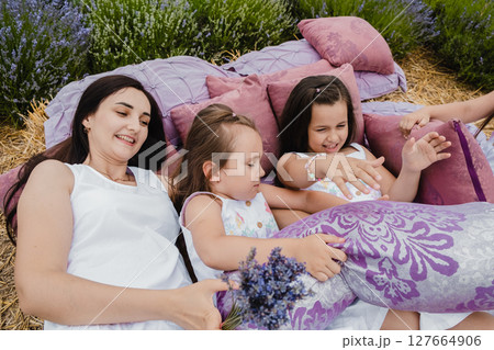 The happy mother and her three daughters snuggle close to each other, creating a perfect family scene 127664906