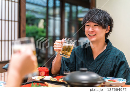 会席料理で生ビールをおいしそうに飲む浴衣姿のカップル 127664975