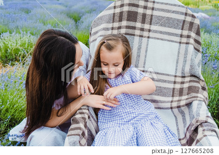 A cute little daughter in a beautiful purple dress sits in a rocking chair 127665208