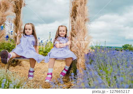 Cute girls are relaxing on a big swing in the middle of a lavender field 127665217