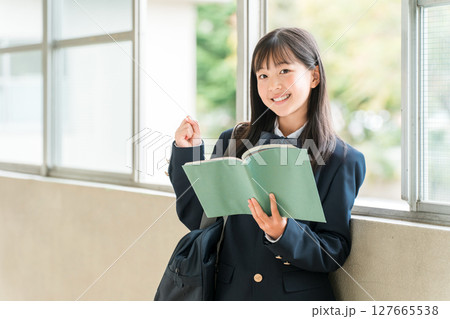 学校の廊下で本を持つ小学生,中学生,高校生の女子生徒 学校の廊下で本を持つ小学生,中学生,高校生の女子生徒 127665538
