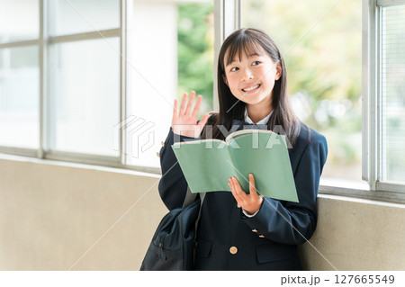 学校の廊下で本を持つ小学生,中学生,高校生の女子生徒 127665549