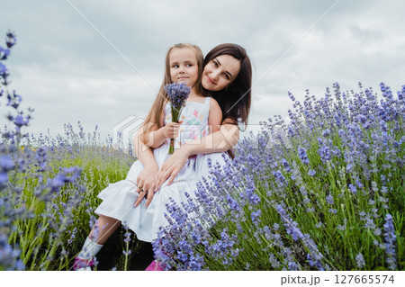 The mother gently embraces her daughter against the backdrop of the lavender field The mother gently embraces her daughter against the backdrop of the lavender field 127665574