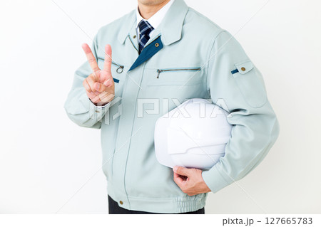 グリーンの作業服を着てヘルメットを持ちピースをするミドル男性ビジネスマン 127665783