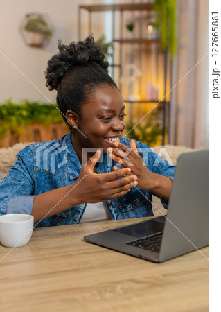 African American woman waving hand while chatting with friends conversation online on laptop at home 127665881