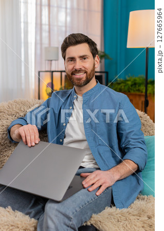 Young man smiling with satisfaction while closing laptop, feeling happy and accomplished after work Young man smiling with satisfaction while closing laptop, feeling happy and accomplished after work 127665964