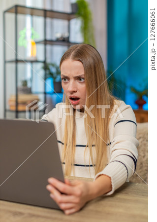 Caucasian woman facing virus error on laptop at home on table, confused, losing data, frustrated Caucasian woman facing virus error on laptop at home on table, confused, losing data, frustrated 127666061