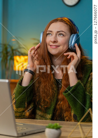 Business woman listening music through wireless headphones relaxing taking a break laptop on table Business woman listening music through wireless headphones relaxing taking a break laptop on table 127666077