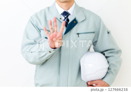 グリーンの作業服を着てヘルメットを持ち指を4本立てるミドル男性ビジネスマン 127666238