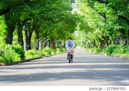 自転車の練習をする5歳の男の子とフォローする父親 127666391