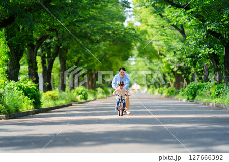 自転車の練習をする5歳の男の子とフォローする父親 127666392