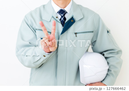 グリーンの作業服を着てヘルメットを持ちピースをするミドル男性ビジネスマン グリーンの作業服を着てヘルメットを持ちピースをするミドル男性ビジネスマン 127666462