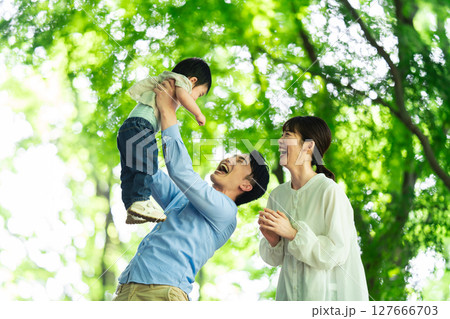 新緑の元で1歳の息子をたかいたかいする父親 新緑の元で1歳の息子をたかいたかいする父親 127666703