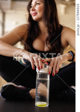 Close-up of plus-size woman with lemon water bottle after workout, body positivity concept 127666928