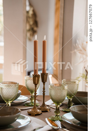 Elegant Table Setting with Peach Candles, Green Glassware, and Antique Brass Holders Rustic Wedding or Dinner Party Atmosphere 127667079