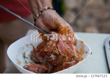 Hands Marinating Cubed Pork Meat in White Bowl with Spices Outdoors. Rustic Food Preparation, Kitchen Scene, Summer BBQ, Seasoning, Reddish-Brown Tones Hands Marinating Cubed Pork Meat in White Bowl with Spices Outdoors. Rustic Food Preparation, Kitchen Scene, Summer BBQ, Seasoning, Reddish-Brown Tones 127667125