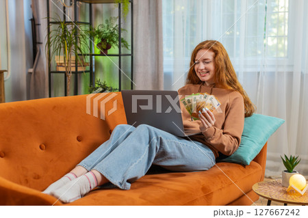Rich happy woman counting money euro cash using laptop calculate domestic bills sitting on sofa 127667242