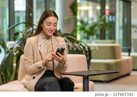 Caucasian business woman using smartphone texting share messages content working in office lobby 127667392