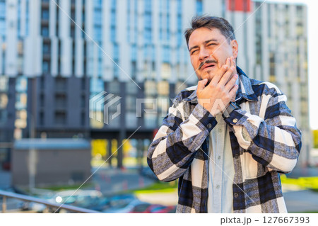 Mature Caucasian businessman feeling toothache bad unpleasant symptoms suffering from pain outdoors Mature Caucasian businessman feeling toothache bad unpleasant symptoms suffering from pain outdoors 127667393