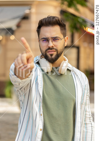 Upset Caucasian man reacting to unpleasant awful idea shaking finger at camera on city urban street Upset Caucasian man reacting to unpleasant awful idea shaking finger at camera on city urban street 127667478