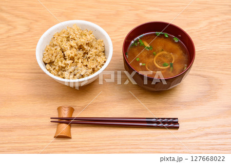 木目テーブル背景の茶碗に玄米ごはんと味噌汁 127668022
