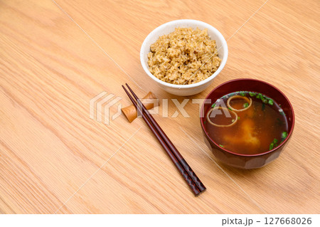 木目テーブル背景の茶碗に玄米ごはんと味噌汁 127668026