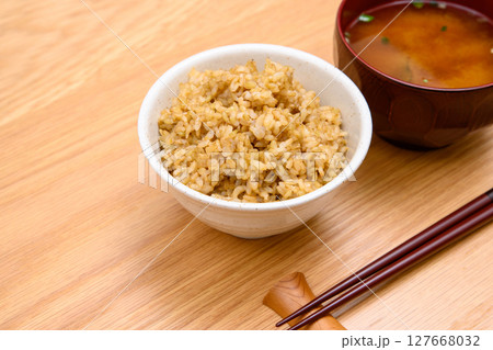 木目テーブル背景の茶碗に玄米ごはんと味噌汁 127668032